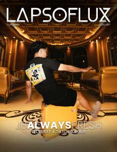 Dynamic young man performing a dance pose on a yellow suitcase inside an opulent, vintage-style lounge with gold accents and ornate ceiling, promoting LAPSOFLUX with a focus on celebrity style and TikTok barber trends.