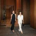 Two elegantly dressed guests walking through Four Seasons Hotel Toronto with evening handbags