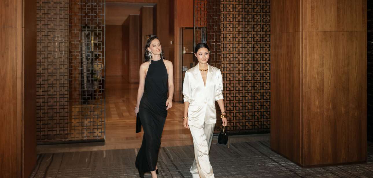 Two elegantly dressed guests walking through Four Seasons Hotel Toronto with evening handbags