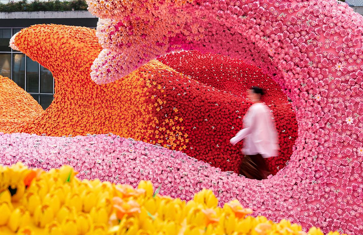 Visitor walking between pink and orange LEGO flower waves at TANK Shanghai