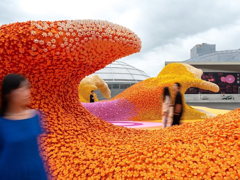Visitors beside a curling orange wave assembled from LEGO flowers