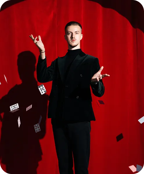 Roman Royss tossing playing cards in front of a red curtain